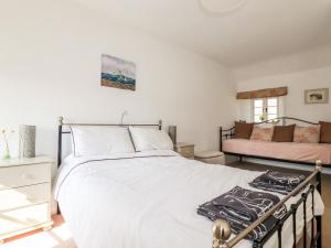 a bedroom with a large white bed and a couch at Slate Cottage in Helland