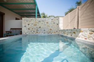 a swimming pool in a house with a stone wall at Arodamos Studios & Apts in Kissamos