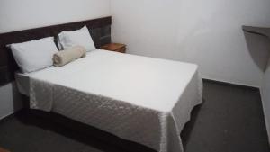 a bedroom with a white bed with a pillow on it at Pousada Tucano in Prado
