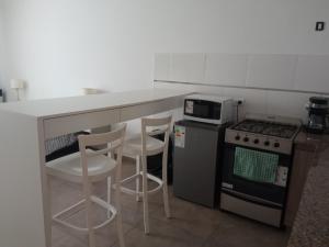 a kitchen with a counter and two stools and a stove at Apart Pm Domus in Necochea