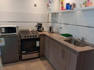 a small kitchen with a stove and a sink at Apart Pm Domus in Necochea