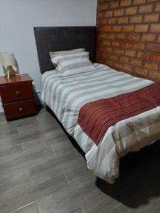 1 dormitorio con cama y pared de ladrillo en Benkawasi Experience Huaraz, en Huaraz