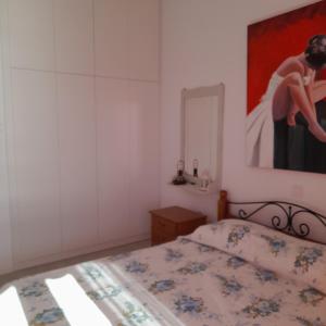 a bedroom with a bed and a painting on the wall at Esperides Sea in Andros +13 photos