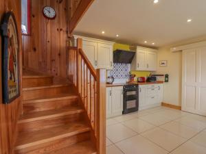 a kitchen with white cabinets and stairs in a house at Red Chimneys Cottage in Husabost