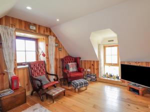 a living room with two chairs and a flat screen tv at Red Chimneys Cottage in Husabost