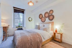 a bedroom with a bed with plates on the wall at The Malthouse - Naturally styled central apartment in Cirencester