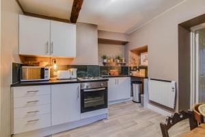 a large kitchen with white cabinets and appliances at The Malthouse - Naturally styled central apartment in Cirencester