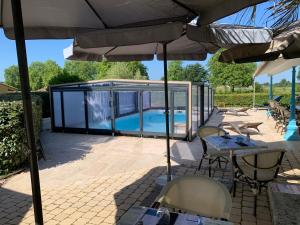 a patio with a table and chairs under an umbrella at Le Melchior in Sainte-Terre