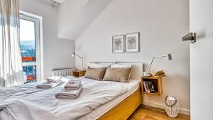 ein weißes Schlafzimmer mit einem großen Bett und einem Fenster in der Unterkunft Apartament Skandynawski 54 - 5D Apartments in Świeradów-Zdrój