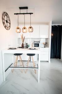 a white kitchen with a table and two stools at "LE PERSIAN" Studio à 3 min de la GARE, 10min du centre commercial, WIFI, PARKING in Evry-Courcouronnes