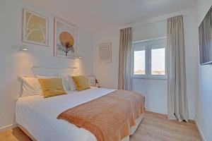 a bedroom with a large white bed with yellow pillows at SEA SALT SAGRES APARTMENT in Sagres