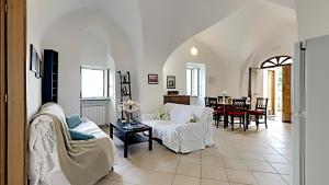 a living room with white furniture and a dining room at The Hidden Garden in Ravello