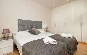 a white bedroom with two towels on a bed at Autèntic Barcelona Monumental in Barcelona