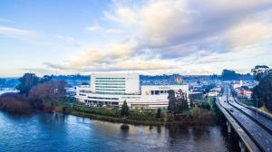 un gran edificio blanco junto a un río con un puente en Sonesta Hotel Osorno, en Osorno