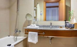 a bathroom with a sink and a mirror and a tub at Sonesta Hotel Osorno in Osorno