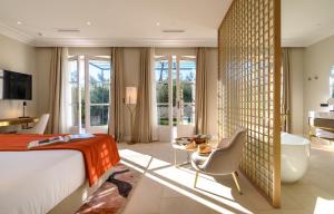 a bedroom with a bed and a desk and a tub at Domaine de Valmouriane in Saint-Rémy-de-Provence