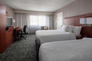 a hotel room with two beds and a desk and a television at Sonesta Select Los Angeles Torrance South Bay in Torrance