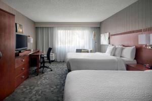 a hotel room with two beds and a desk and a television at Sonesta Select Los Angeles Torrance South Bay in Torrance