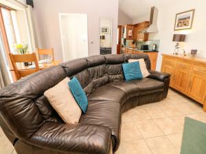 a brown leather couch in a living room with blue pillows at Swallow Barn in Buxton