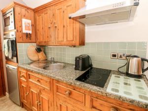 a kitchen with wooden cabinets and a sink at Swallow Barn in Buxton