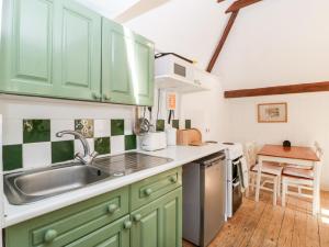 uma cozinha com armários verdes e um lavatório em The Old Stable em Sherborne