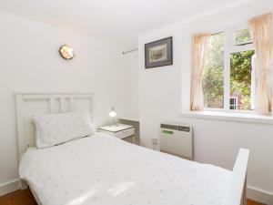 a white bedroom with a bed and a window at The Old Stable in Sherborne