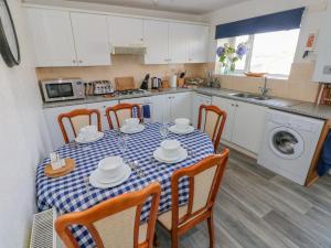 uma cozinha com mesa e cadeiras e uma cozinha com máquina de lavar roupa em The Beach House em Llanelli
