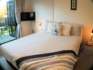 a bedroom with a large bed with pillows and a television at STUDIO ON KINGS in Wanaka