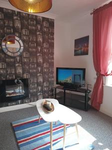 a living room with a table and a tv at Sunny Beach top apartment 4 in Skegness