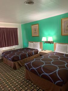 two beds in a hotel room with green walls at Village Inn Salina in Salina