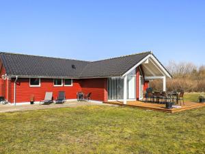 een rood huis met een terras en stoelen erop bij Holiday home Brovst XVI in Brovst