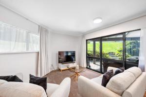 salon z 2 białymi kanapami i telewizorem w obiekcie Acacia Heights - Garden Cottage - Taupo w mieście Taupo