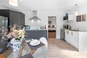 a kitchen with a table with a vase of flowers at Acacia Heights - Garden Cottage - Taupo in Taupo