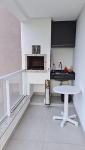a white kitchen with a table and a fireplace at Apartamento encantador na praia de Navegantes in Navegantes