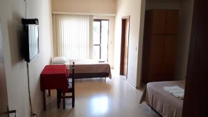 um quarto com uma cama, uma mesa e uma janela em Hotel Dona Marta em Maria da Fé