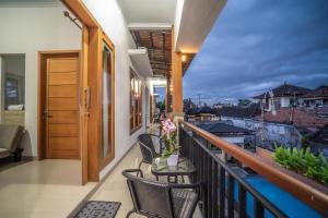 a balcony with chairs and a table with flowers on it at Umah Odah Homestay in Ubud