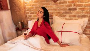 a woman sitting on a bed with a glass of wine at Chalé Formoso - Chalé Romântico com Hidromassagem in Serra de São Bento