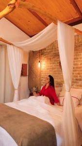 a woman sitting on a bed in a bedroom at Chalé Formoso - Chalé Romântico com Hidromassagem in Serra de São Bento