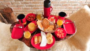 a table topped with red plates of food and drinks at Chalé Formoso - Chalé Romântico com Hidromassagem in Serra de São Bento