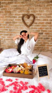 a woman laying on a bed with a tray of food at Chalé Formoso - Chalé Romântico com Hidromassagem in Serra de São Bento