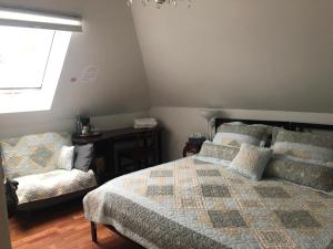 a bedroom with a bed and a chair and a window at Ambassador B&B in Ottawa
