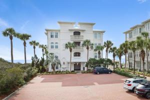 Un gran edificio blanco con palmeras en un estacionamiento. en Sunset Serenade, en Rosemary Beach