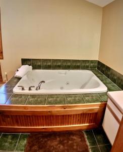 a bathroom with a bath tub with green tile at Cedar Creek Cabins #1 - Giant Spa Tub, Large Wooded Porch, Full Kitchen, 1 Bedroom in Eureka Springs