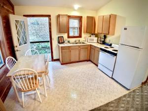 a kitchen with a table and a white refrigerator at Cedar Creek Cabins #1 - Giant Spa Tub, Large Wooded Porch, Full Kitchen, 1 Bedroom in Eureka Springs
