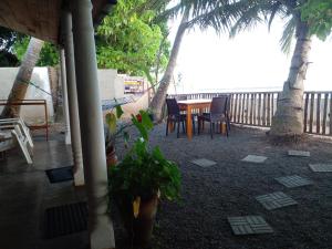 a patio with a table and chairs and palm trees at Seaside View in Mirissa