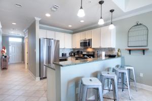 a kitchen with white cabinets and a bar with stools at The Whart Unit 505 condo in Orange Beach