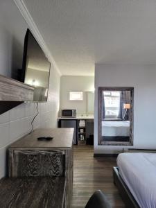 a bedroom with a bed and a desk and a mirror at Parkside Inn in Grande Prairie