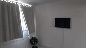 um quarto branco com uma televisão e uma janela em Apartamento aconchegante 12 min da praia em Cabo Frio