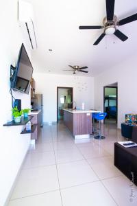 Jaco Modern & Beach Apartment - Lapa Living A1 في جاكو: غرفة معيشة مع مروحة سقف وتلفزيون