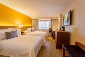 a hotel room with two beds and a television at Camino Real Aeropuerto in Mexico City